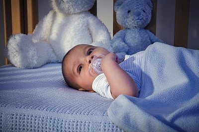 Baby boy and teddy bears in crib at night